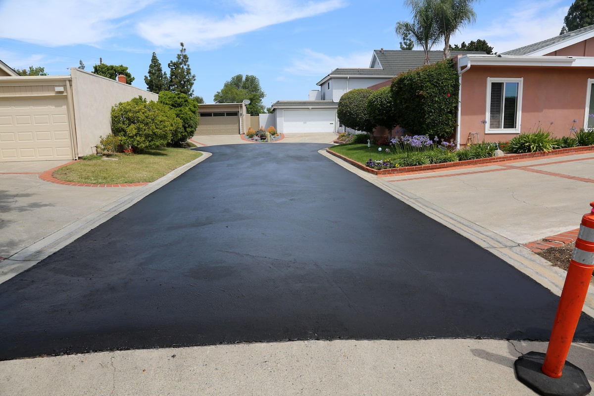 Черен асфалт оформя път между къщи